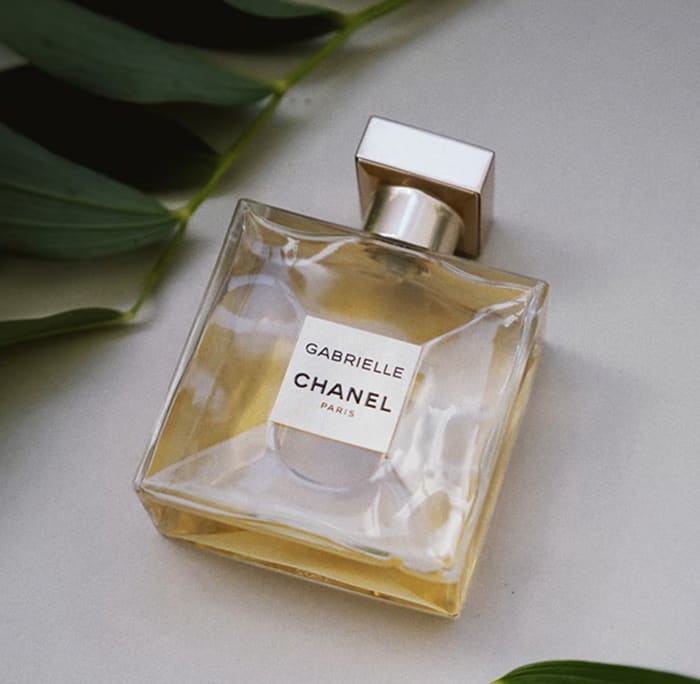 Gabrielle Essence Eau De Parfum bottle on a leaf-strewn surface